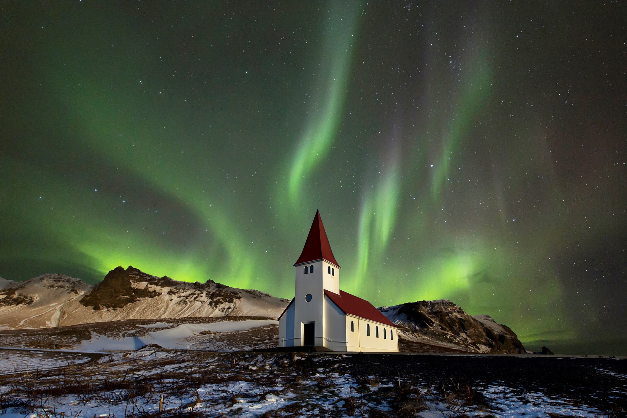 Northern lights (aurora borealis) over the Víkurkirkja church at Vík í Mýrdal, Iceland.