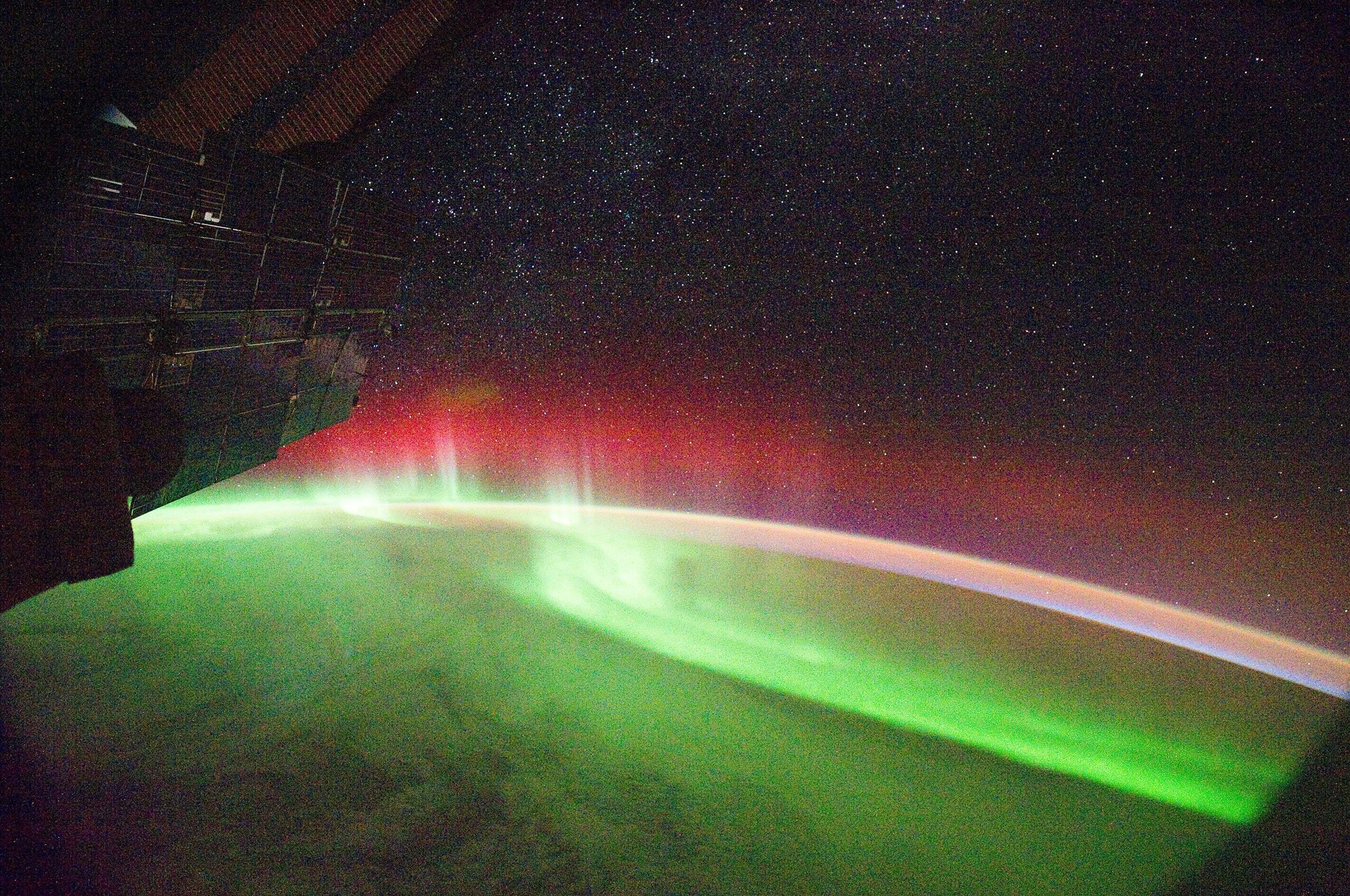 An image from the International Space Station shows a bright green and red aurora over our planet.