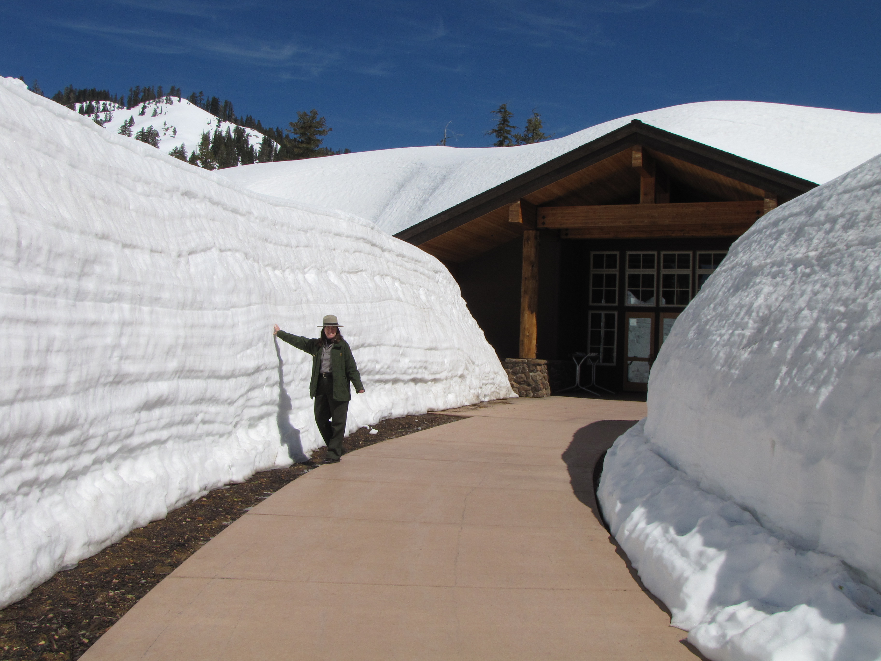 A ranger stands next to a snow wall lining the path to the Kohm Yah-mah-nee Visitor Center at Lassen National Park in Northern California in 2010.